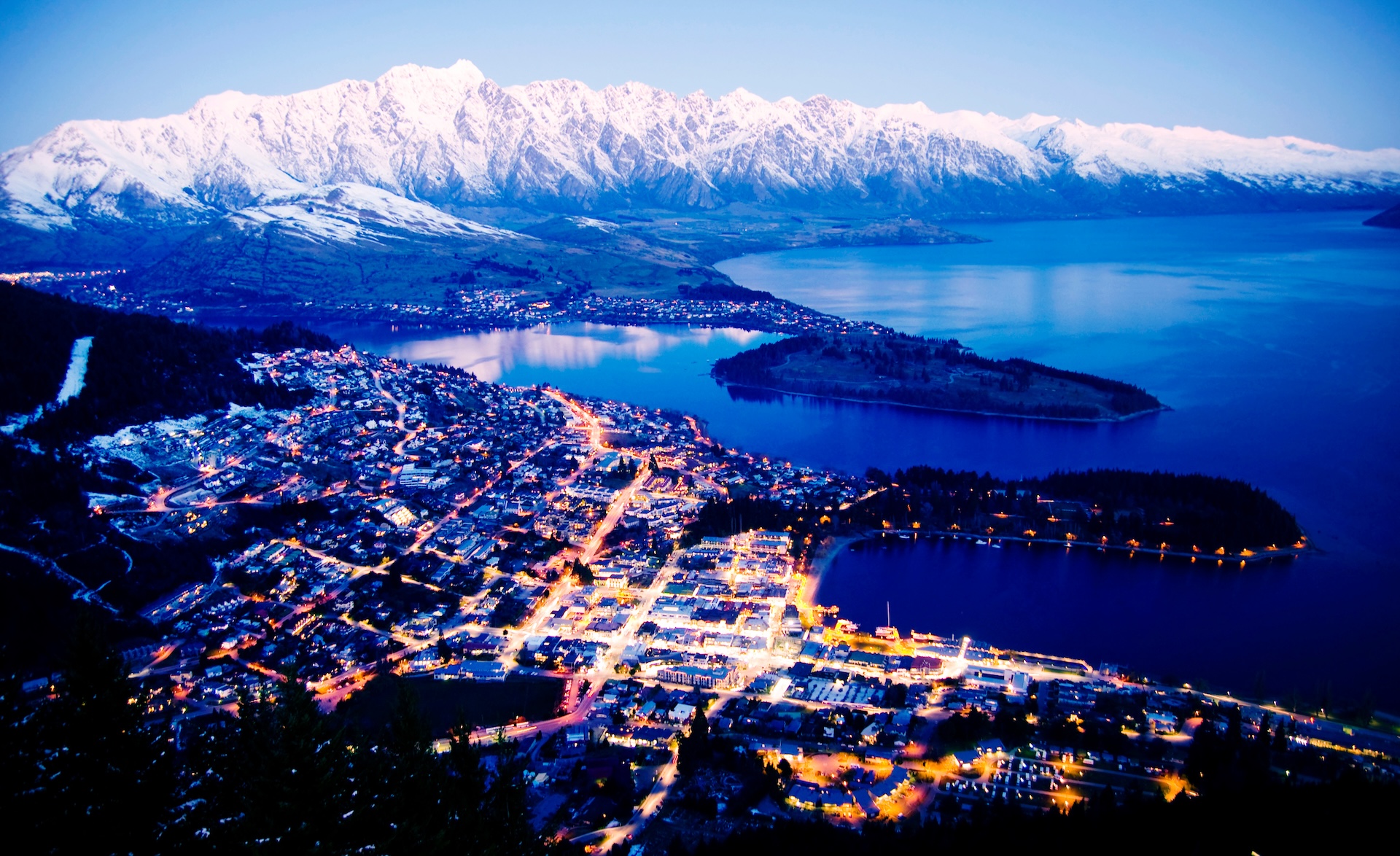 Queenstown photographed at night with bright lights and Remarkables mountain range in background